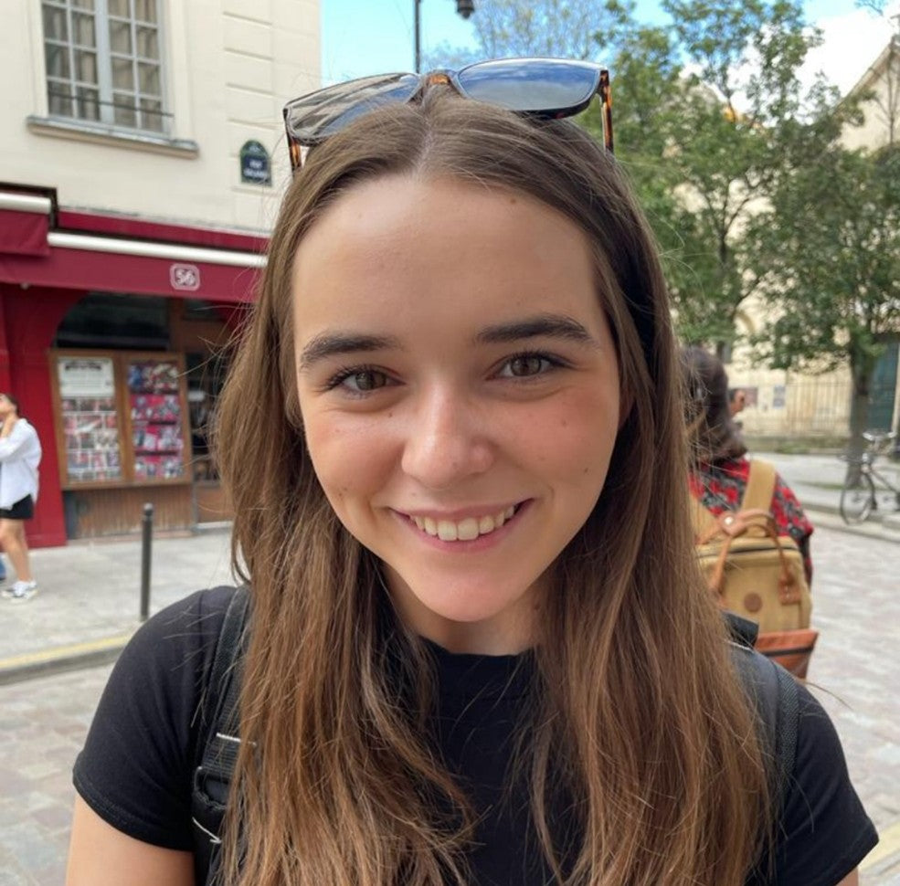Woman with sunglasses on head smiling outdoors in a city setting