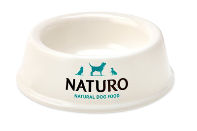 A white Naturo dog bowl with a non-slip base and a logo that reads 'Naturo Natural Dog Food' on the side.