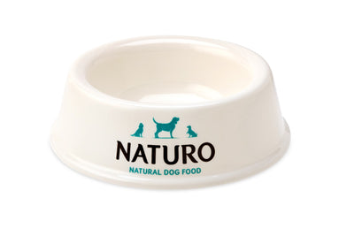 A white Naturo brand dog bowl with a logo and text on the side, featuring a non-slip base.