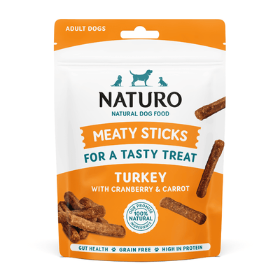 Package of Naturo meaty sticks treats for adult dogs with turkey, cranberry, and carrot on a light blue background.