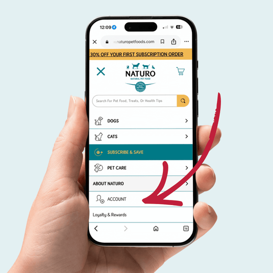 Hand holding a smartphone displaying the Naturo Pet Foods app on a light blue background