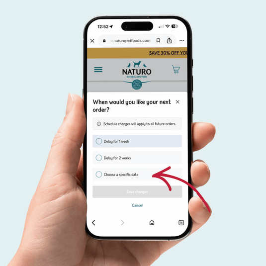 Hand holding a smartphone displaying the Naturo app with an order scheduling screen.