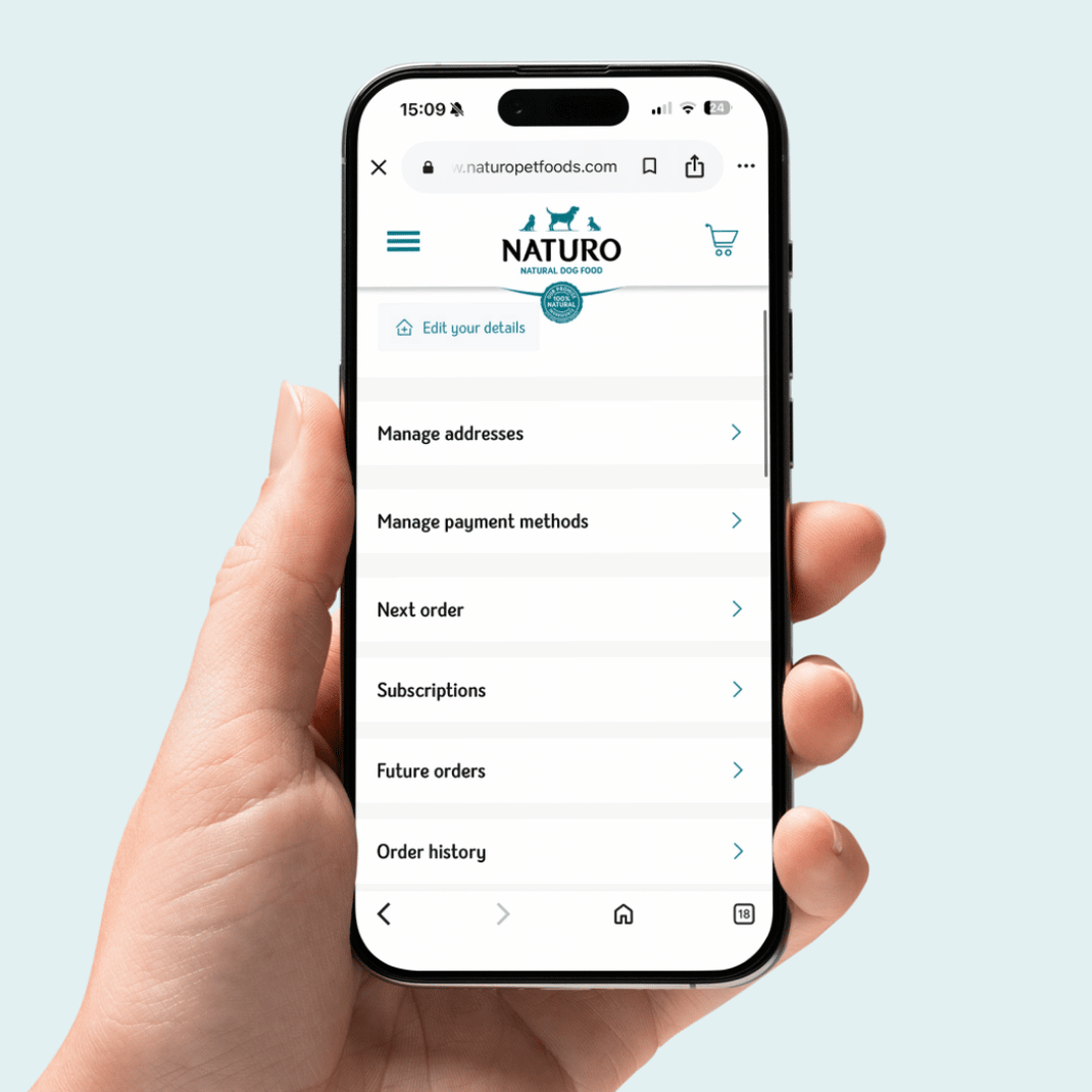 Hand holding a smartphone displaying the NATURO app on a light blue background