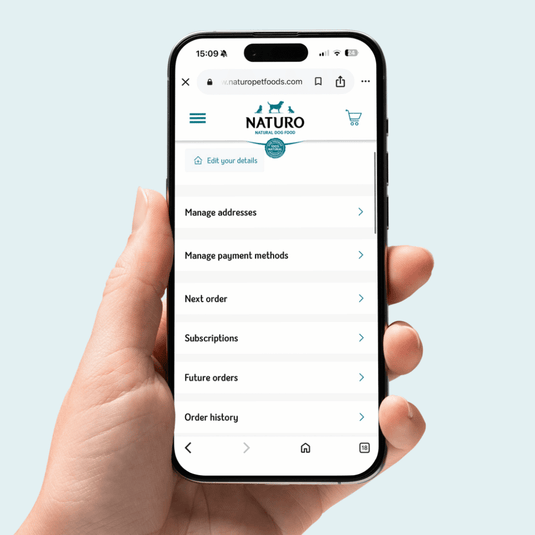 Hand holding a smartphone displaying the NATURO app on a light blue background